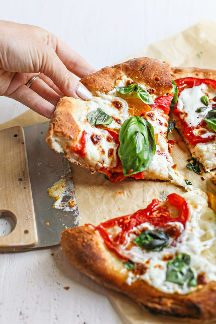 woman serving a slice of caprese pizza