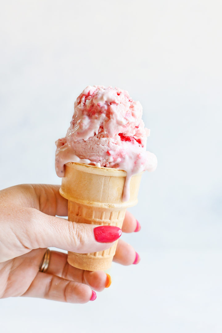 woman holding an ice cream cone with strawberry frozen yogurt