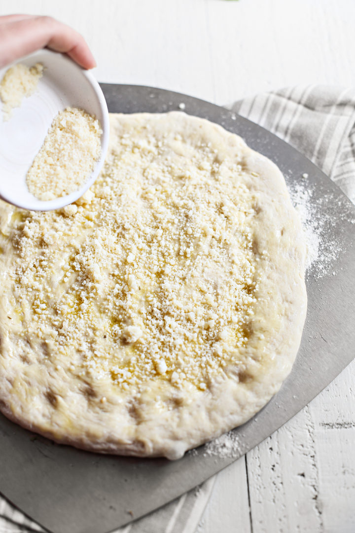 adding cheese on top of the caprese pizza dough