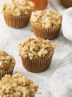 apple crumble muffins on a light background with a kitchen towel