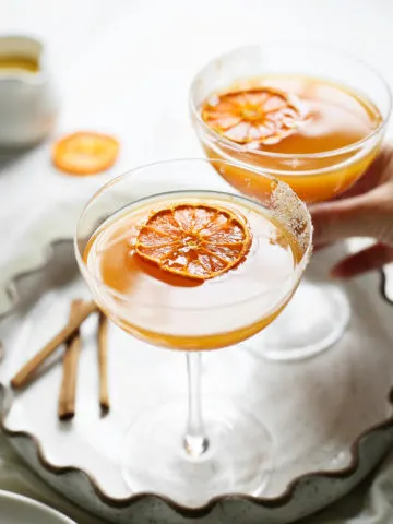 woman picking up a glass of pumpkin martini