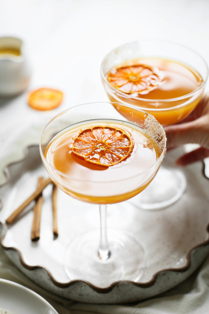 woman picking up a glass of pumpkin martini