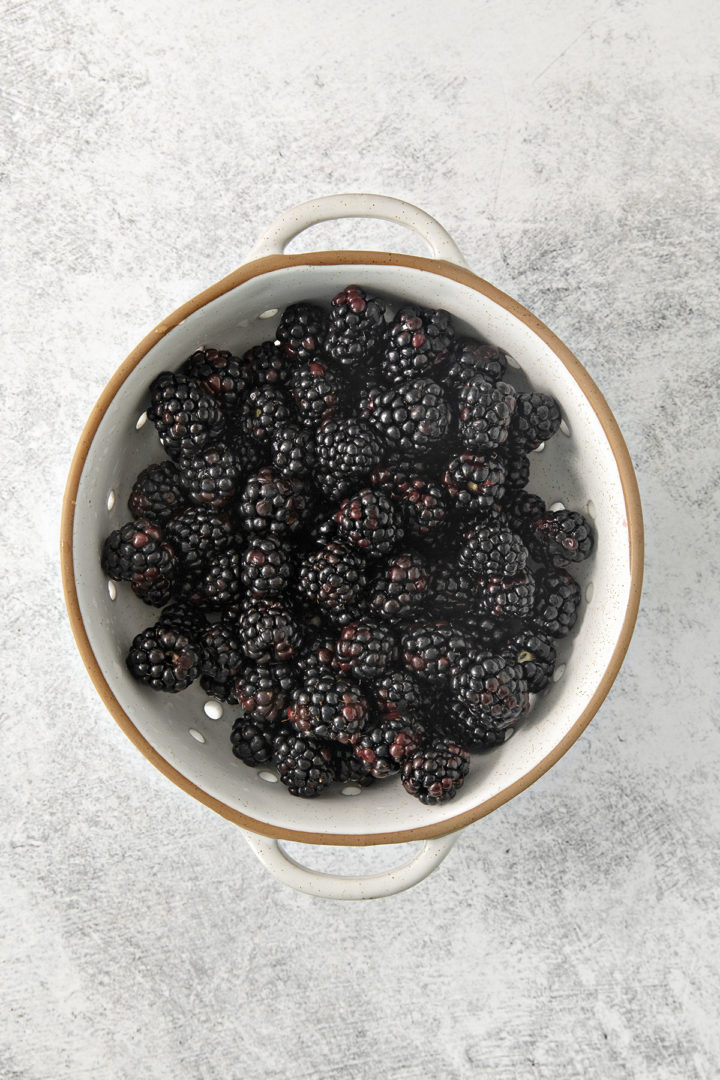 blackberries in a colander being washed before freezing