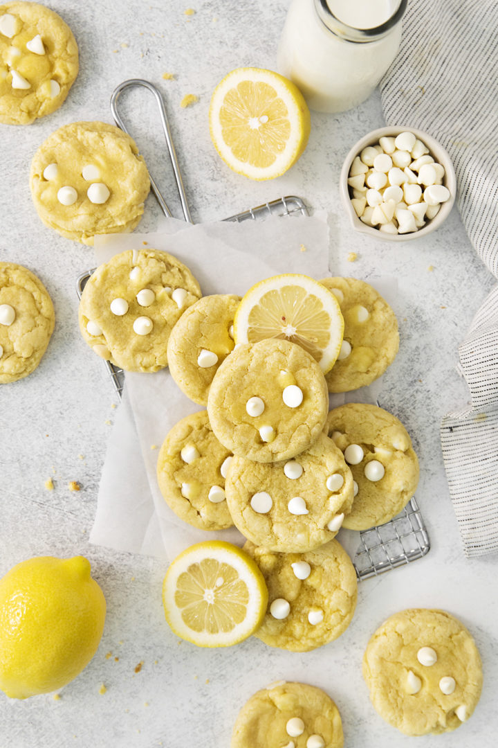 overhead photo of gluten free lemon cookies on a wire rack with fresh lemons and white chocolate
