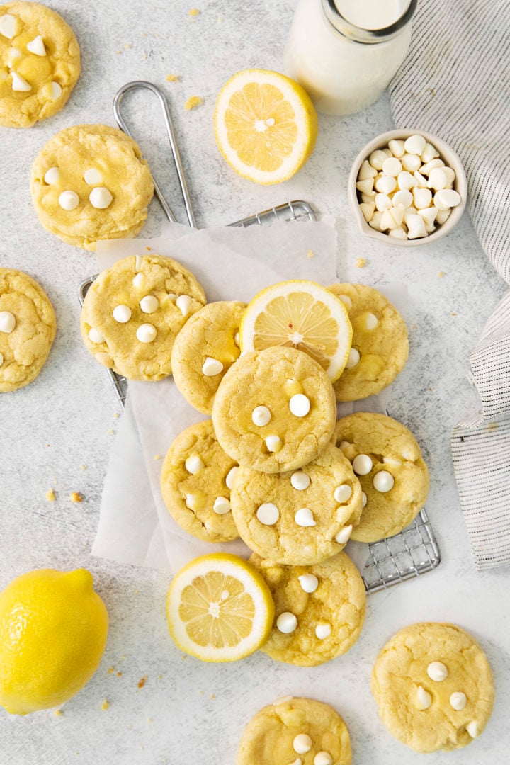 overhead photo of gluten free lemon cookies on a wire rack with fresh lemons and white chocolate