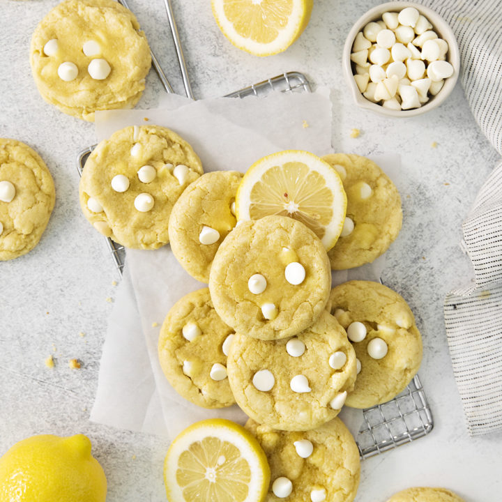 overhead photo of gluten free lemon cookies arranged on a wire rack with fresh lemons and white chocolate chips