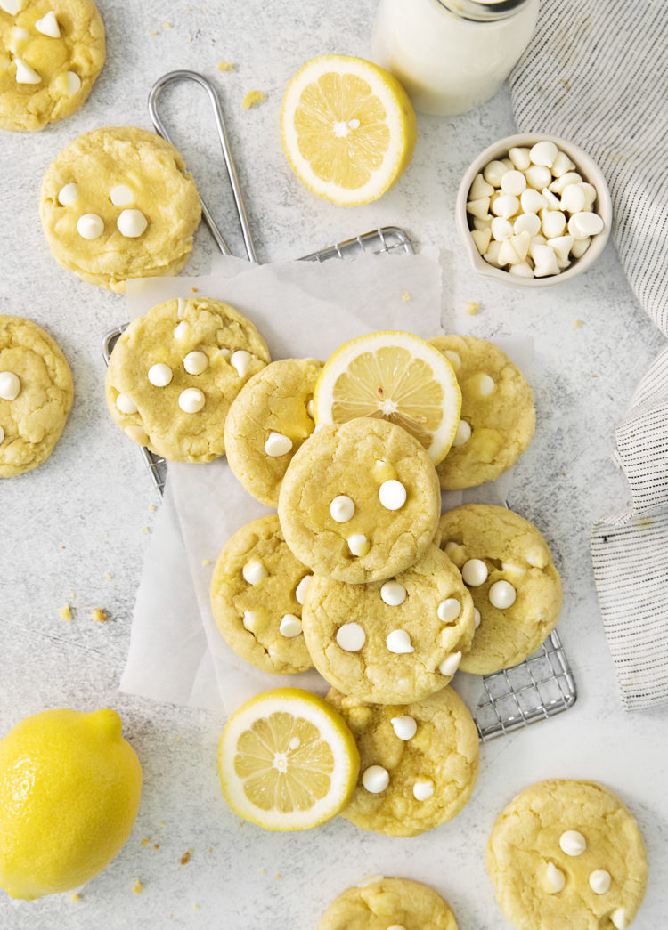 overhead photo of gluten free lemon cookies arranged on a wire rack with fresh lemons and white chocolate chips