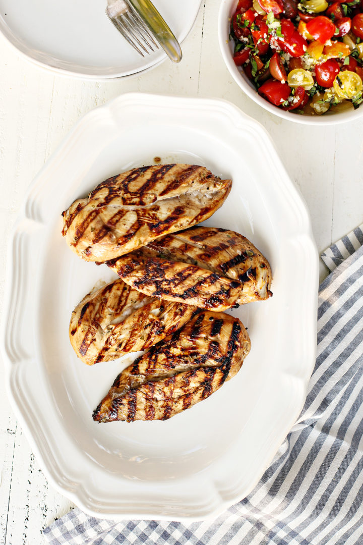 a white platter with grilled chicken breasts that have been marinated in this balsamic chicken marinade
