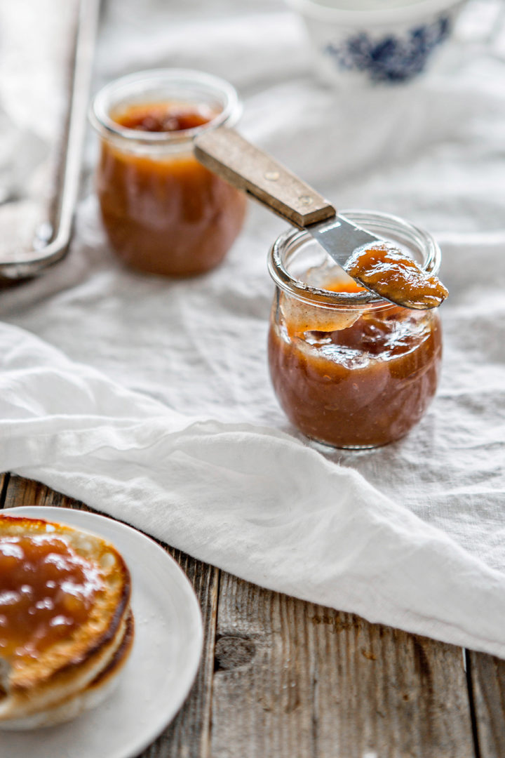 two jars of this pear butter recipe on a white table cloth with a knife
