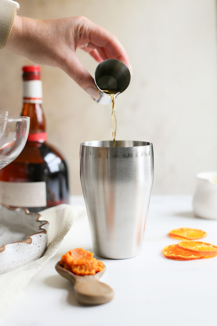 pouring grand marnier to make a pumpkin martini recipe