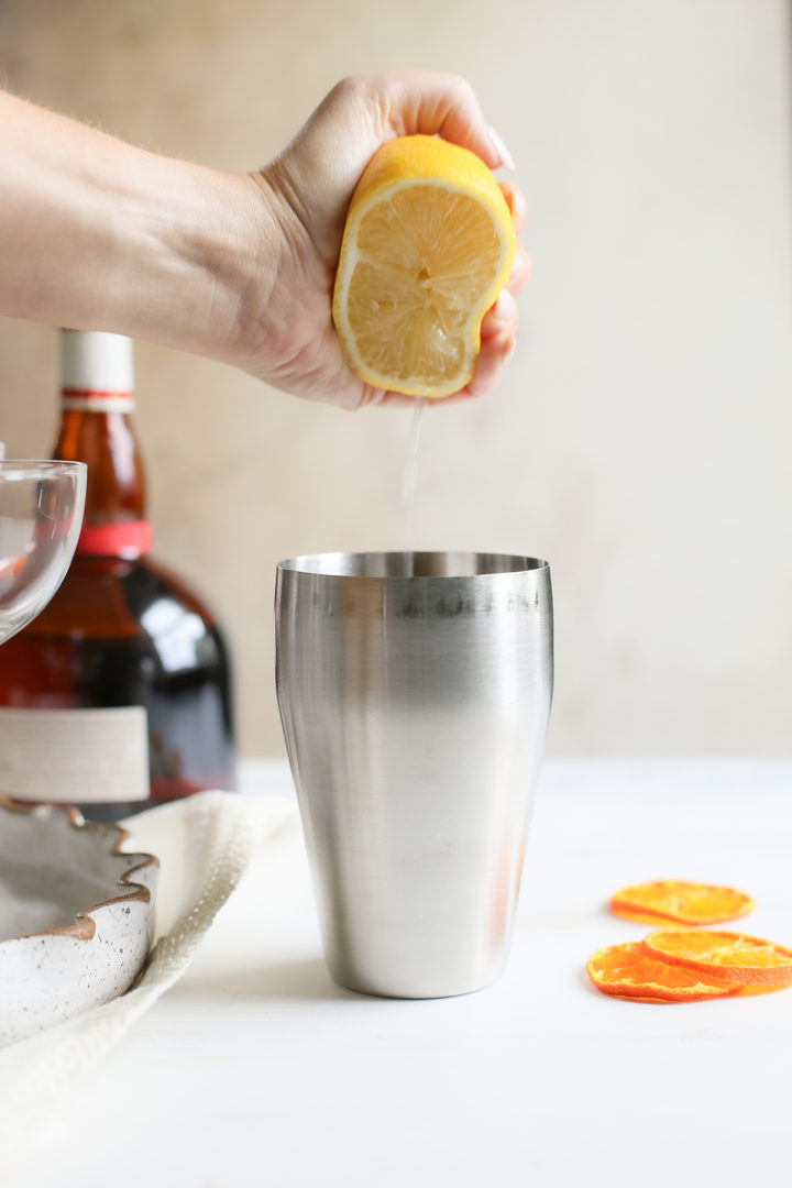 squeezing lemon juice into the pumpkin martini ingredients