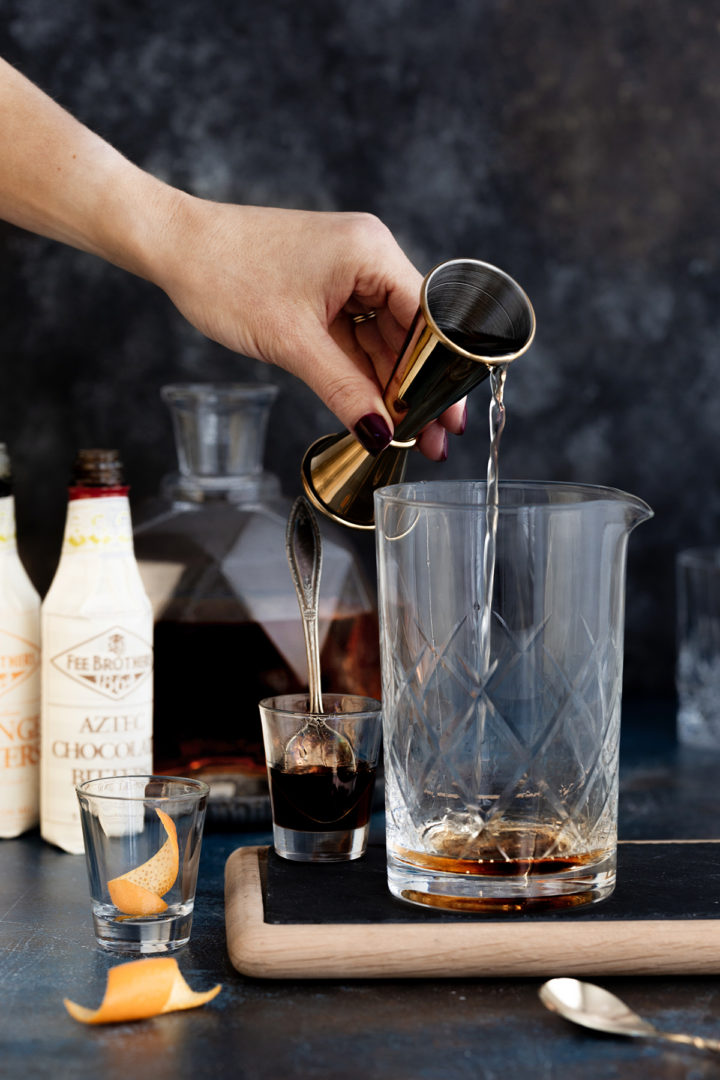 woman adding añejo tequila to a cocktail mixing glass to make a tequila cocktail recipe