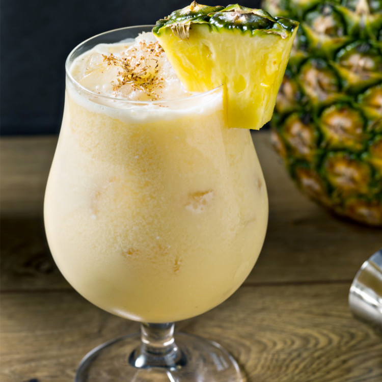 painkiller cocktail in a glass with a pineapple garnish