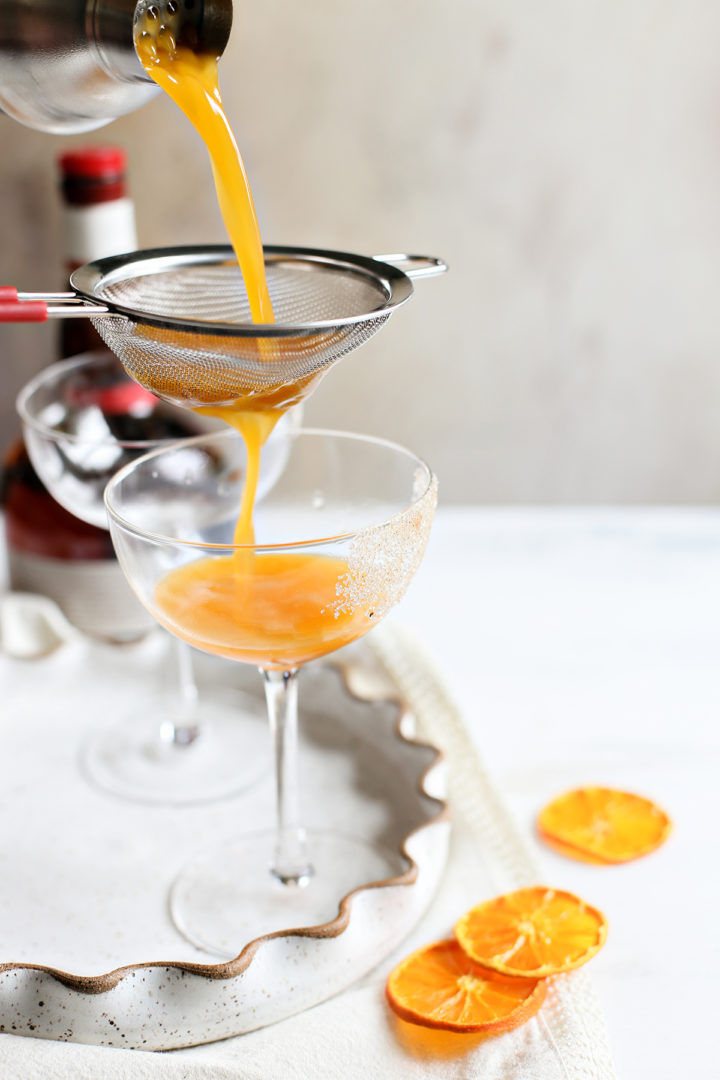 straining the prepared pumpkin spice martini into a cocktail glass