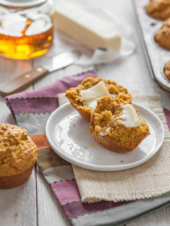 pumpkin cornbread muffin on a plate next to a jar of honey