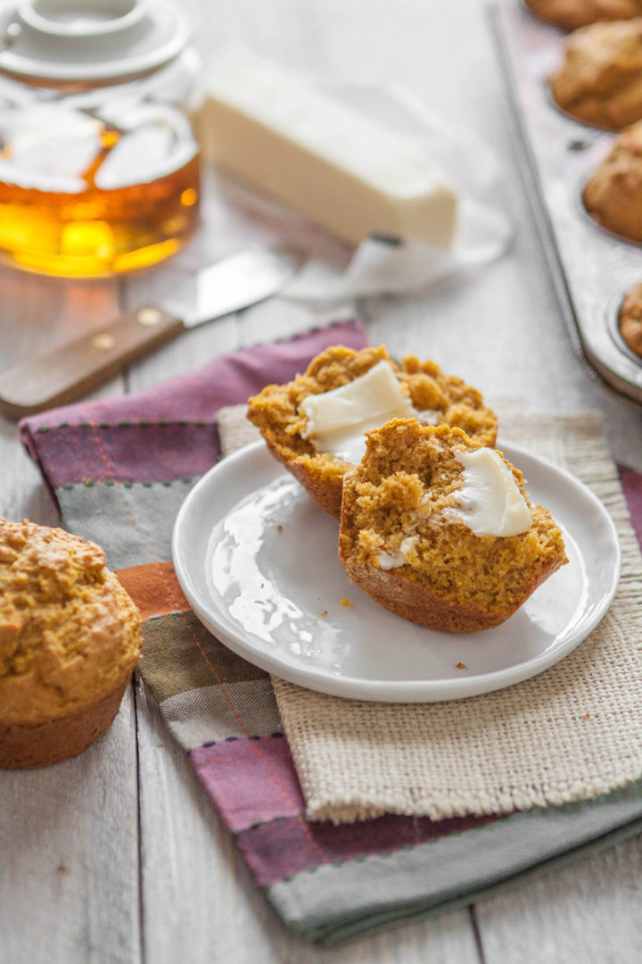 pumpkin cornbread muffin cut in half on a white plate