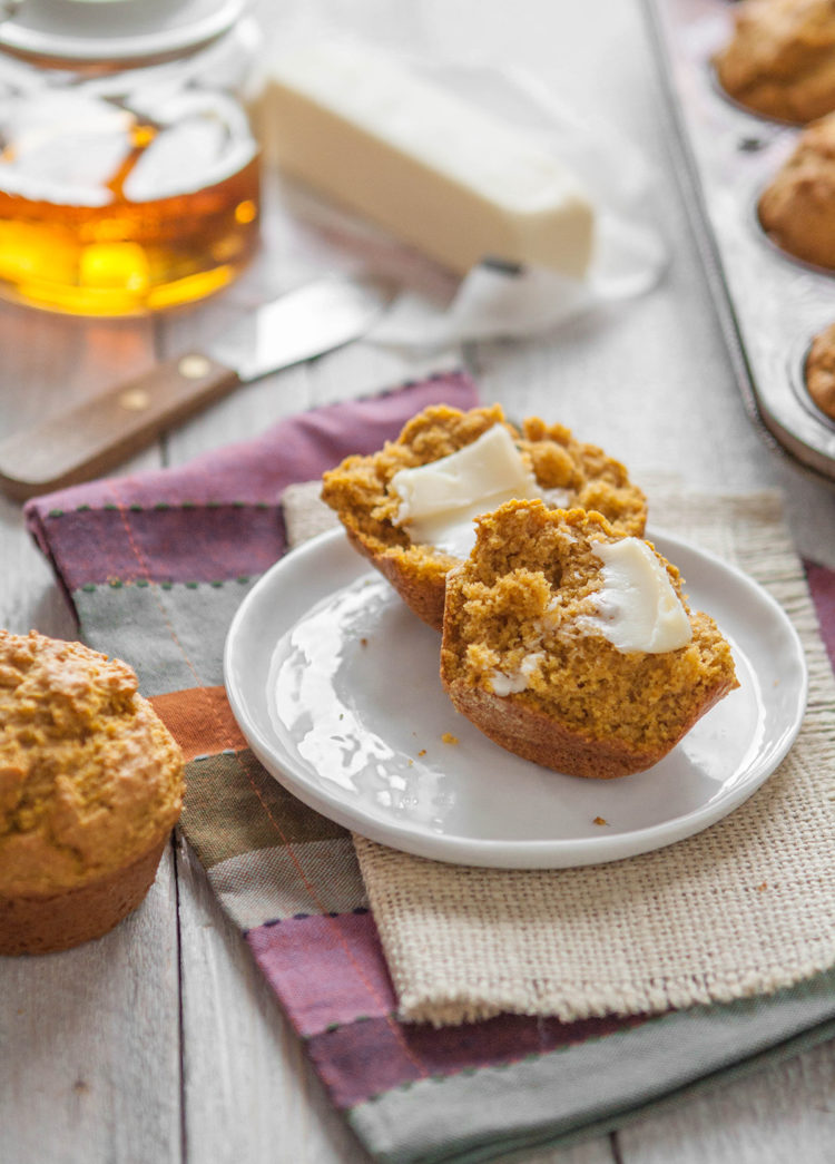 pumpkin cornbread muffin on a plate next to a jar of honey