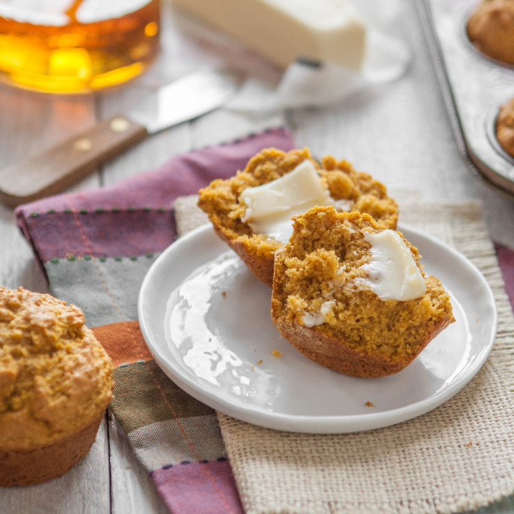 pumpkin cornbread muffin on a plate next to a jar of honey