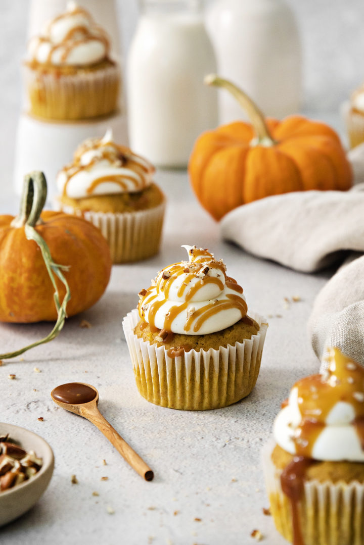 light background with pumpkin cupcakes with cream cheese frosting and mini pumpkins