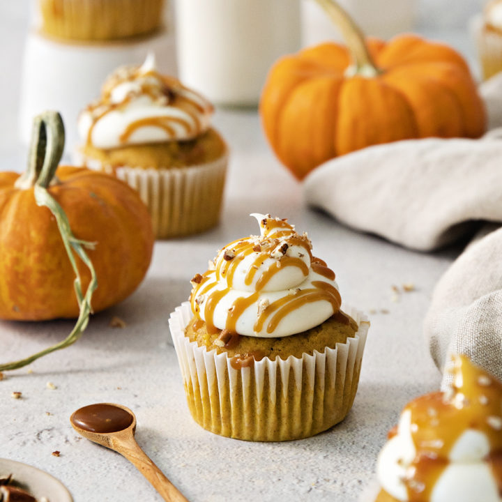 pumpkin cupcakes with cream cheese frosting on a light background with mini pumpkins