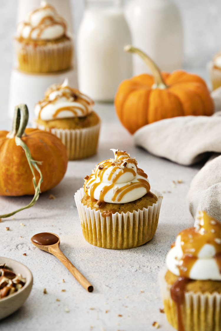pumpkin cupcakes with cream cheese frosting on a light background with mini pumpkins