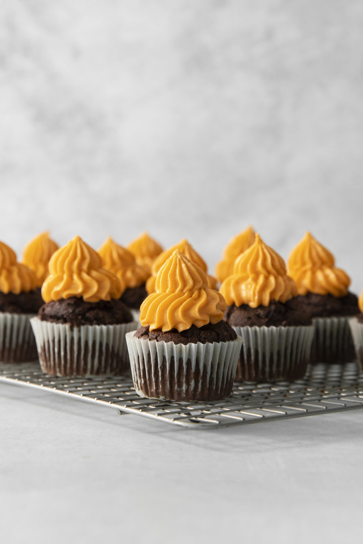 halloween cupcakes on a wire rack with pumpkin frosting