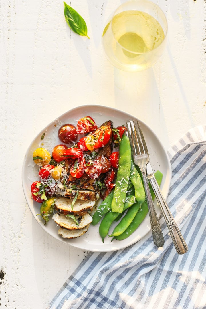 a plate with grilled chicken bruschetta and green beans with a fork and knife