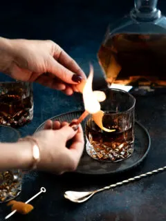 woman making a flamed orange garnish for an old fashioned with tequila