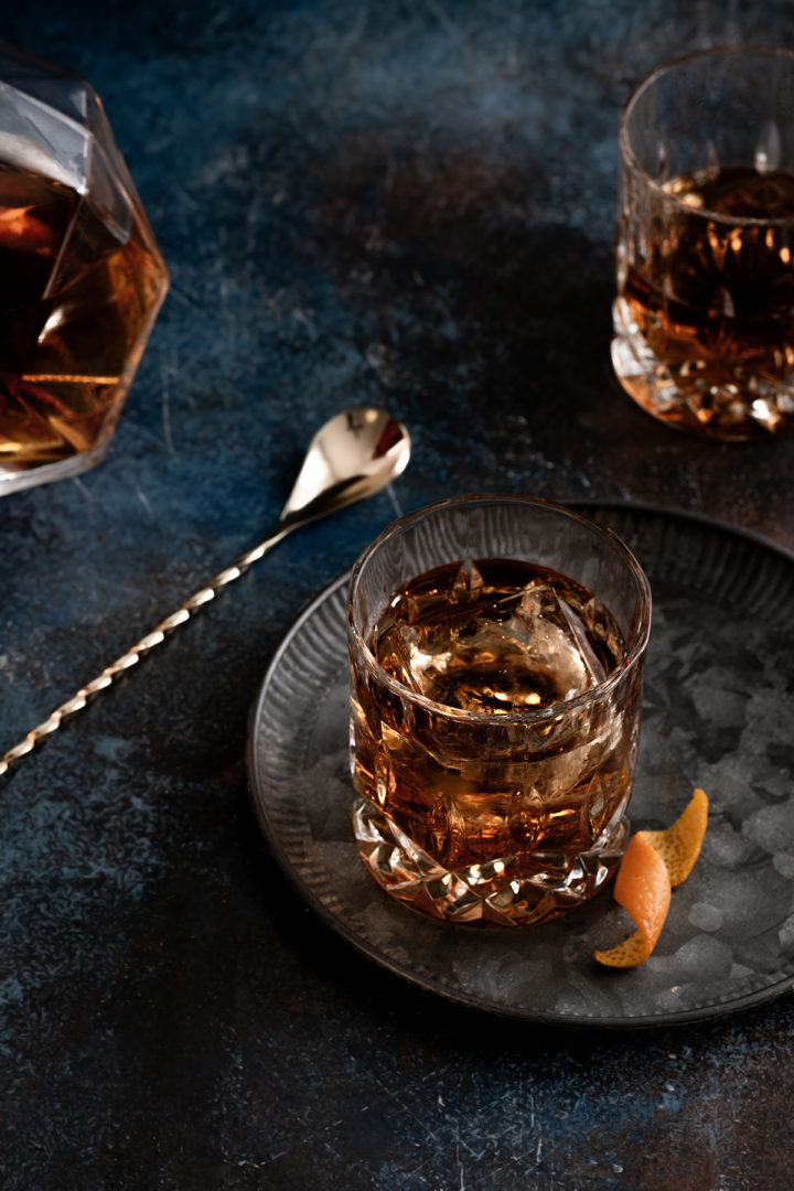 close up photo of a prepared tequila old fashioned in a crystal glass next to an orange twist