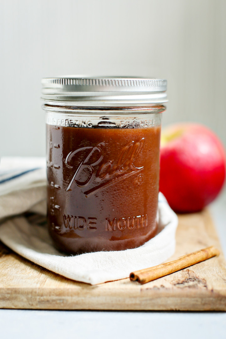 instant pot apple butter in a canning jar on a wooden cutting board