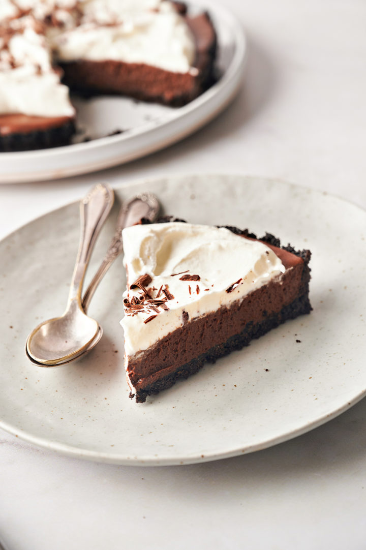 a single slice of chocolate tart on a plate with spoons