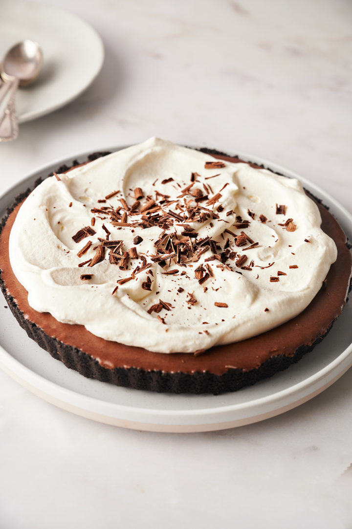 chocolate tart on a serving platter next to a plate with spoons