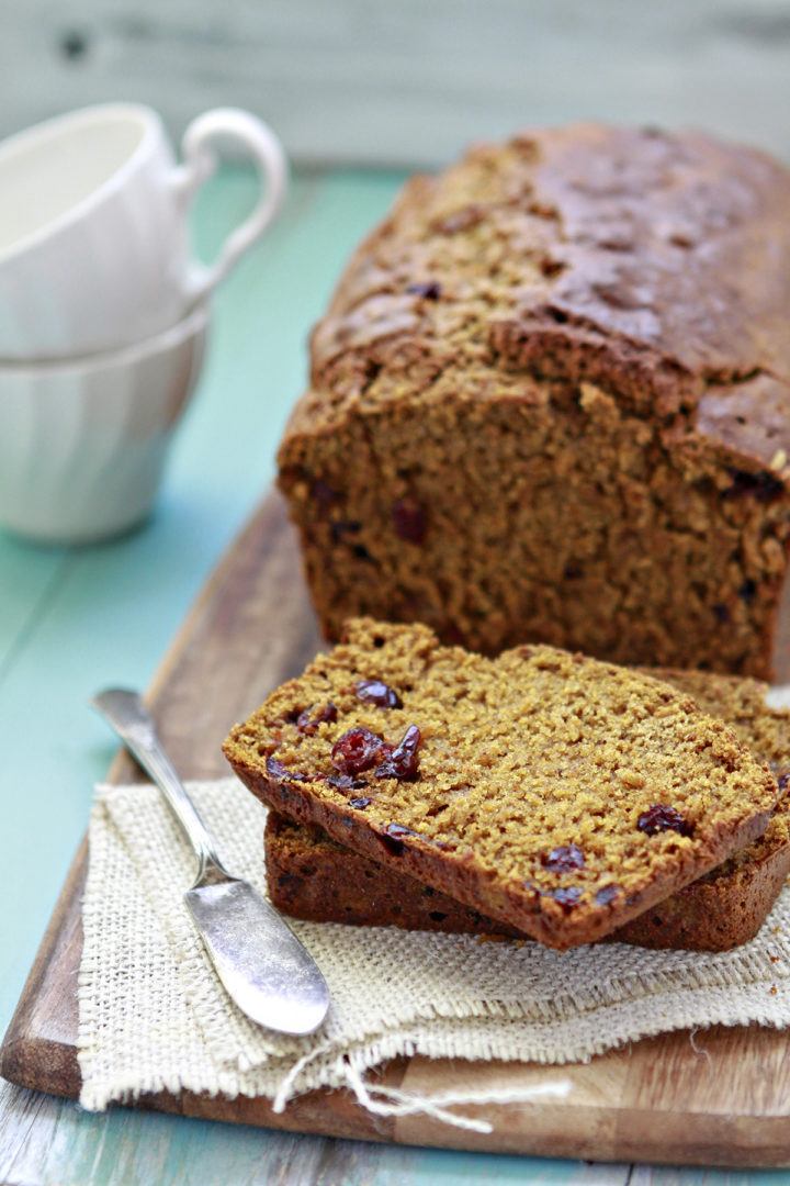 a loaf of pumpkin cranberry bread on a cutting board