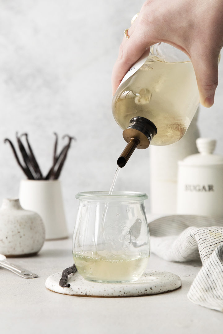woman pouring vanilla syrup into a glass