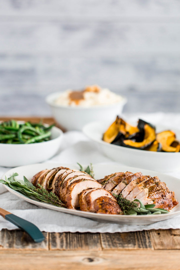 a table with serving dishes and a platter of turkey slices