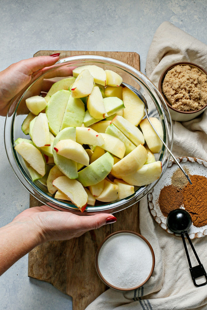 woman holding a bowl of sliced apples to make apple butter with