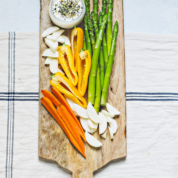 blanched asparagus on a wooden cutting board with other vegetables