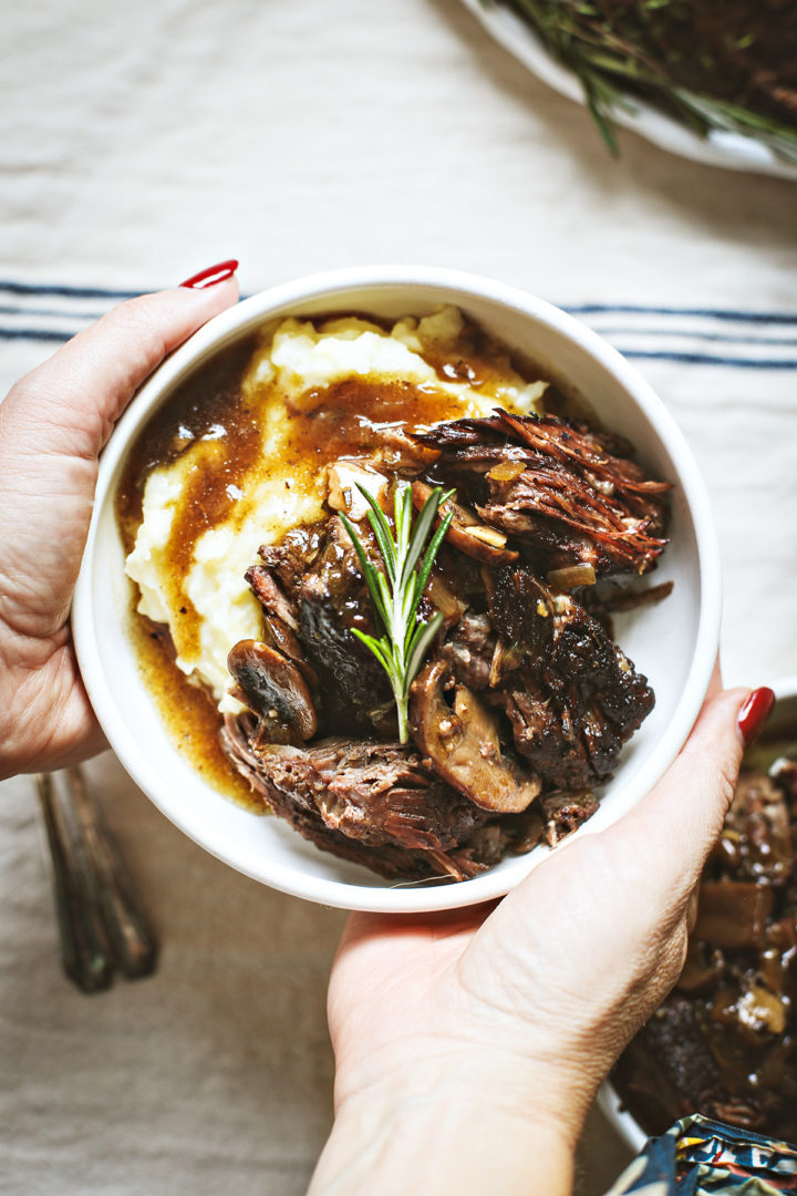 woman holding a plate with mashed potatoes served with this easy pot roast recipe	