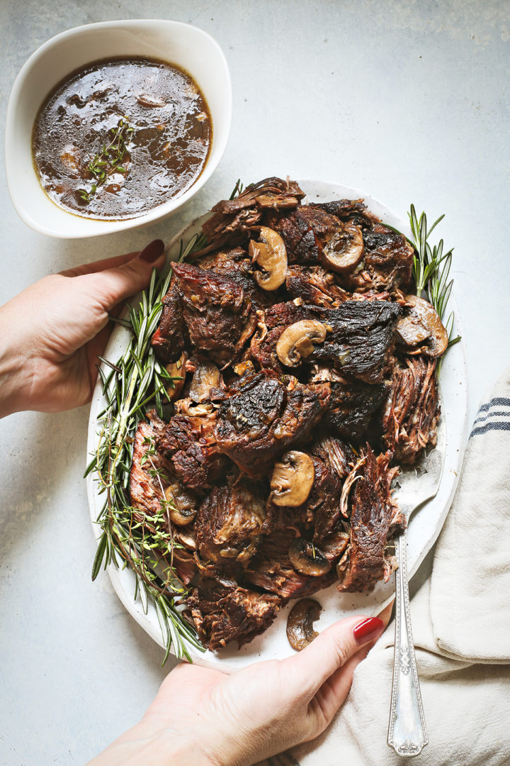 woman holding a platter with a cooke Instant Pot chuck pot roast 
