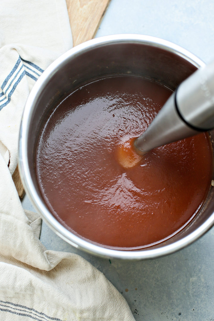 instant pot apple butter being blended with an immersion blender after pressure cooking