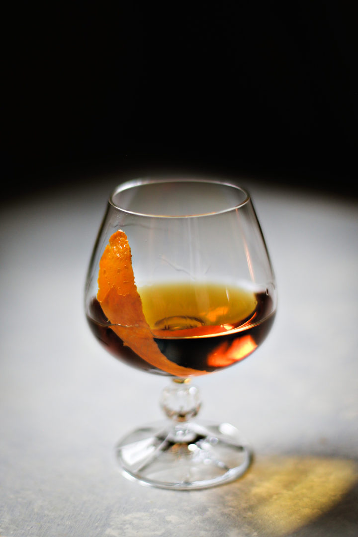 photo of a cocktail with a flamed orange peel garnish