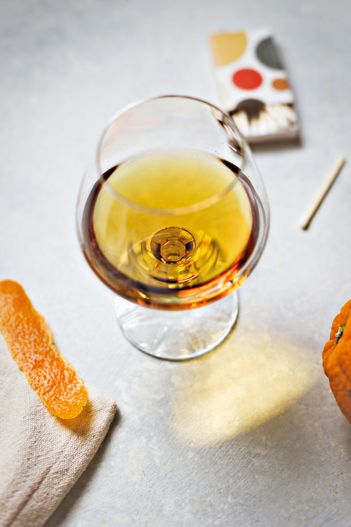 cocktail in a glass next to an orange peel garnish