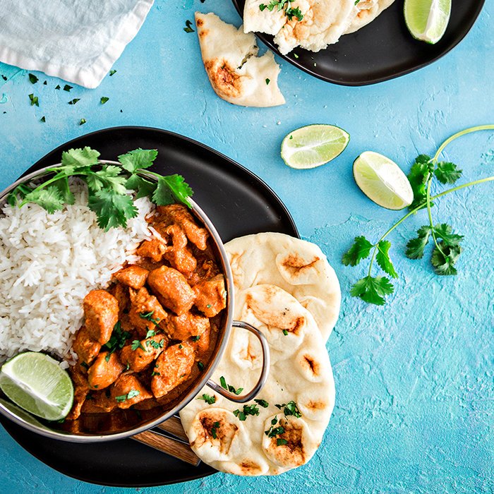 bowl of indian butter chicken on a blue background