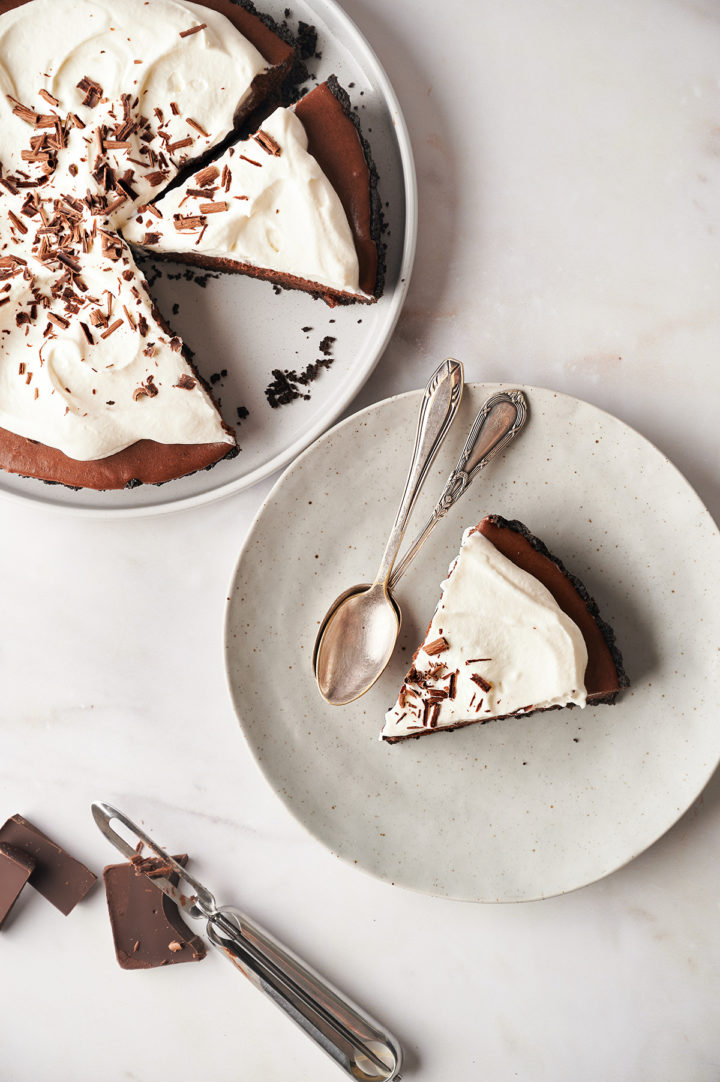 overhead photo of a slice of chocolate tart on a plate with spoons