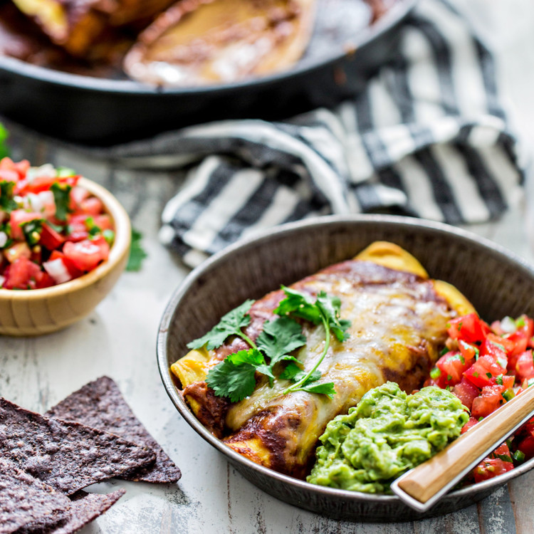 chicken enchiladas on a serving plate with guacamole and pico de gallo