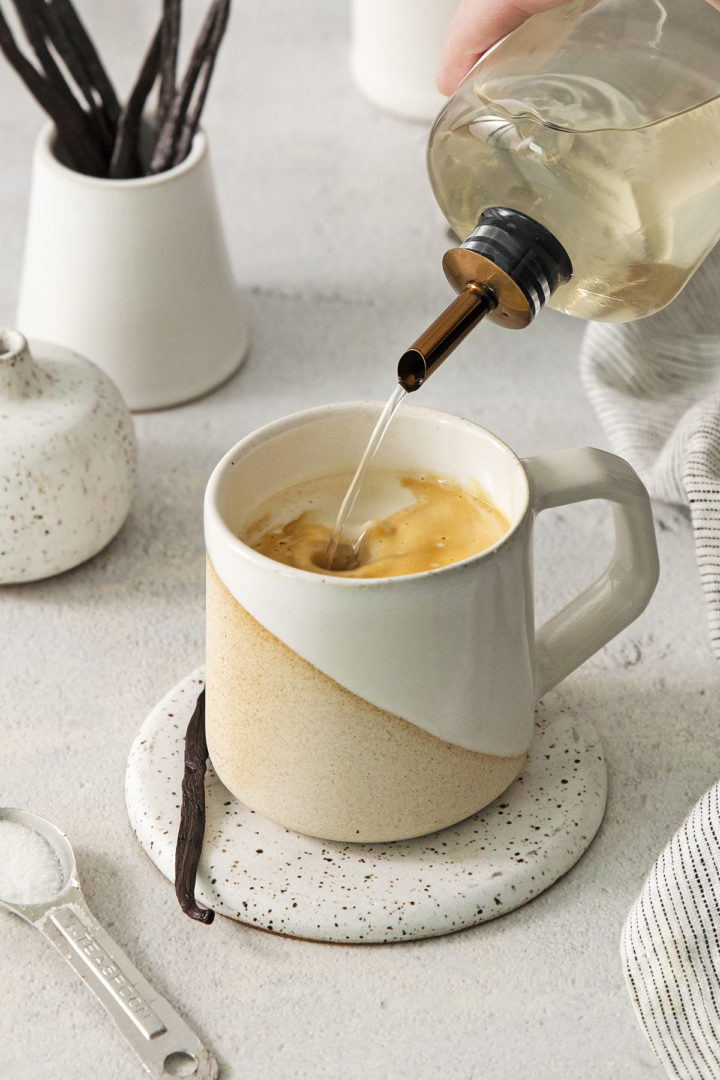 pouring vanilla coffee syrup into a mug with coffee