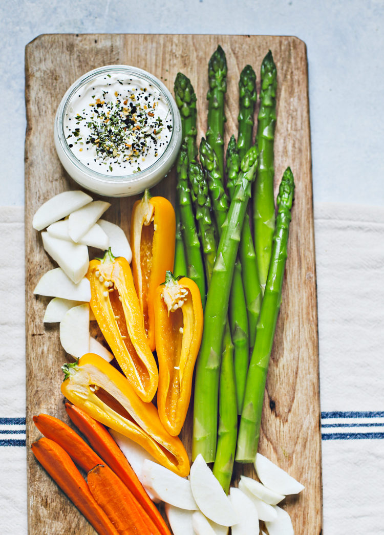 wooden cutting board with blanched asparagus and cut veggies