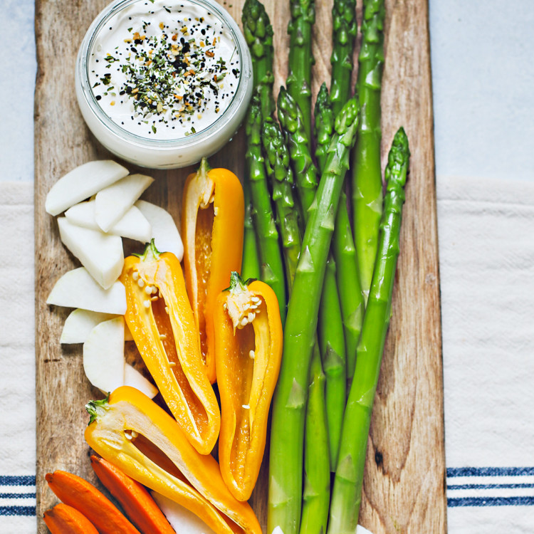 wooden cutting board with blanched asparagus and cut veggies