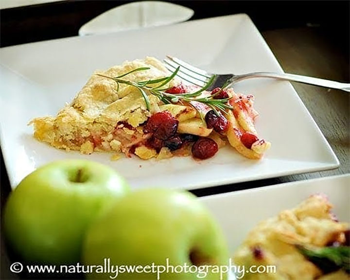 a slice of apple cranberry galette on a square white plate with a fork