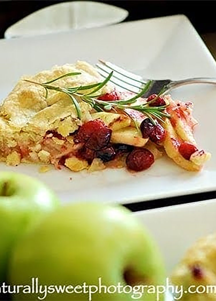 a slice of apple cranberry galette on a square white plate with a fork